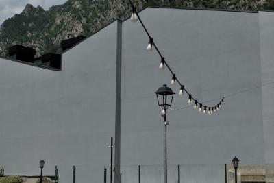 photograph “VI.2021” par David Farreny — www.farreny.net — Andorre, Andorra, Andorre-la-Vieille, Andorra la Vella, ville, city, capitale, capital, mur, wall, béton, concrete, montagne, mountain, gris, grey, gray, lampadaires, street lamps, grillage, fence, clôture, fencing, bâtiment, building, rocher, rock, lampes, lamps, ampoules, bulbs, décoration, decoration, ornemental, cheminées, chimneys, câbles, cables, fil, wire, caméra, vidéo, video, camera, métal, metal, Pyrénées, Pyrenees