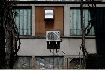 photograph “III.2012” par David Farreny — www.farreny.net — France, bâtiment, immeuble, building, ville, city, béton, concrete, métal, metal, climatisation, air conditioning, unité extérieure, external unit, fenêtres, windows, grillage, clôture, fence, fencing, végétation, ciment, cement, haie, hedge, plastique, plastic, Occitanie, Aveyron, Rouergue, Espalion