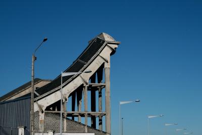 photograph “I.2011” par David Farreny — www.farreny.net — France, Auvergne, Puy-de-Dôme, Clermont-Ferrand, Montferrand, usine, factory, Michelin, béton, concrete, tôle ondulée, corrugated iron, métal, metal, industrie, industry, clôture, grillage, fence, fencing, lampadaires, réverbères, lamps, street lamps, piste d'essai, perspective