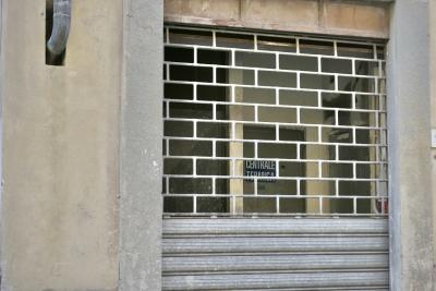 photograph “VIII.2022 — Centrale termica” par David Farreny — www.farreny.net — Italie, Italia, Italy, Toscane, Toscana, Tuscany, Arezzo, Montevarchi, bâtiment, immeuble, building, ciment, cement, entrée, entrance, grille, railing, métal, metal, gouttière, drainpipe, porte, door, panneau, sign, centrale termica, centrale thermique, thermal power station