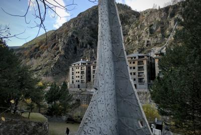 photograph “XI.2022 — Climb” par David Farreny — www.farreny.net — Andorre, Andorra, Canillo, vallée, valley, montagne, mountain, rocher, rock, immeubles, bâtiments, buildings, mur, wall, escalade, climbing, béton, concrete, triangulaire, triangular, arbres, trees, passant, passer-by, piéton, pedestrian