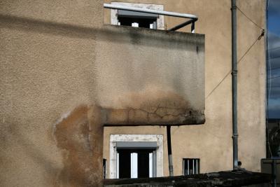 photograph “II.2010 — Charity” par David Farreny — www.farreny.net — France, balcon, balcony, mur, wall, crépi, roughcast, fenêtres, windows, gouttière, drainpipe, fils, wires, charité, charity, humidité, dampness, moisture, damp, Occitanie, Aveyron, Rouergue, Rodez