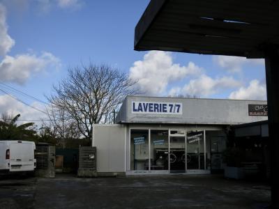 photograph “XII.2024 — Whatever” par David Farreny — www.farreny.net — France, Occitanie, Gascogne, Gascony, Lomagne, Tarn-et-Garonne, Beaumont-de-Lomagne, laverie, laundry, laundromat, station-service, gas station, fermée, closed, fourgonnette, van, arbre, tree, branches, branchages, hiver, winter, enseignes, sigsn, Laverie 7/7, restaurant, chez, numéro, téléphone, phone, number, 05.63.65.97.81, béton, concrete, vitrine, window, vitre, glass, verre, machines à laver, lave-linge, washing machines, séchoirs grande capacité, machines 8 et 18 kg, couvertures, couettes, large capacity dryers, 8 and 18 kg machines, blankets, duvets, câbles, cables, fils, wires, chaises, chairs, porte, door, boîte à lettres, mailbox