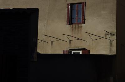 photograph “II.2014” par David Farreny — www.farreny.net — France, maison, house, façade, facade, mur, wall, fenêtres, windows, volets, shutters, métal, metal, rouge, red, barres, bars, ombre, shadow, ciment, cement, rideaux, curtains, noir, black, fissure, crack, Occitanie, Aveyron, Rouergue, Réquista