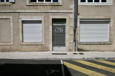 photograph “V.2018” par David Farreny — www.farreny.net — France, Occitanie, Gascogne, Gascony, Gers, Condom, ville, city, bourgade, town, rue, street, trottoir, pavement, bitume, blacktop, asphalte, asphalt, peinture, paint, bandes, stripes, jaune, yellow, goutttières, drainpipes, métal, metal, porte, door, fenêtres, windows, stores, pierre, stone, logo, handicapé, disabled, ombre, shadow, câbles, cables, fils, wires, enseigne, CMA