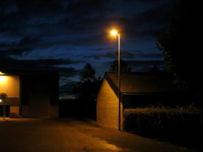 photograph “X.2013 — At night” par David Farreny — www.farreny.net — France, soir, evening, nuit, night, bâtiment, building, maison, house, lampadaire, réverbère, street lamp, arbres, trees, ville, city, métal, metal, haie, hedge, nuages, clouds, lumières, lights, obscurité, darkness, obscur, dark, toit, roof, mur, wall, panier, basket, Occitanie, Rouergue, Aveyron, Olemps