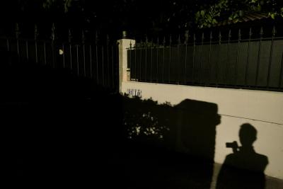 photograph “X.2022 — Buto” par David Farreny — www.farreny.net — France, Occitanie, Haute-Garonne, Toulouse, maison, house, Buto, nuit, night, portail, gate, grille, railings, muret, low wall, arbres, trees, toit, roof, ombre, shadow, homme, man, photographe, photographer, silhouette, autoportrait, selfportrait, métal, metal