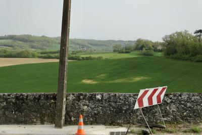 photograph “IV.2019 — Memories of Gascony” par David Farreny — www.farreny.net — France, Occitanie, Gascogne, Gers, Jegun, paysage, landscape, campagne, countryside, collines, hills, champ, field, bois, wood, route, road, muret, low wall, pierre, stone, poteau, post, pole, ciment, cement, cône, cone, circulation, traffic, signalisation, plastique, plastic, orange, panneau, sign, maisons, houses, horizon