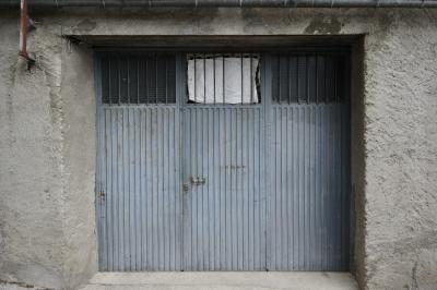 photograph “VII.2023” par David Farreny — www.farreny.net — Andorre, Andorra, Canillo, bâtiment, building, hangar, entrepôt, warehouse, entrée, entrance, porte, door, métal, metal, verre, vitre, glass, ciment, cement, gouttière, gutter, rugueux, rough, rouille, rust, rusty