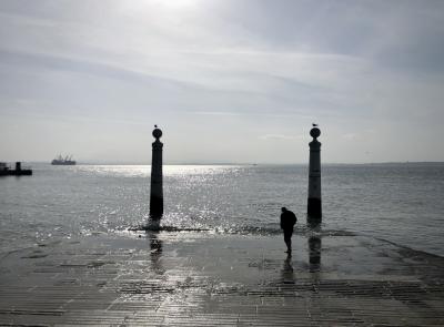 photograph “II.2020 — Whatever” par David Farreny — www.farreny.net — Portugal, Lisbonne, Lisboa, Lisbon, ville, city, capitale, capital, Tage, Tagus, fleuve, river, eau, water, bateaux, boats, homme, man, piéton, pedestrian, horizon, pierre, stone, ciel, sky, nuages, clouds