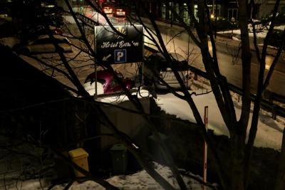 photograph “I.2019” par David Farreny — www.farreny.net — Andorre, Andorra, Andorre-la-Vieille, Andorra la Vella, hiver, winter, nuit, night, soir, evening, neige, snow, route, road, voitures, cars, parking, car park, panneau, sign, arbre, tree, branches, noir, black, poubelles, bins, trash, vitrine, magasin, shop, window, store, bitume, blacktop, asphalt, asphalte, ville, city, capitale, capital, froid, cold