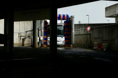 photograph “IV.2024 — Whatever” par David Farreny — www.farreny.net — France, Occitanie, Haute-Garonne, Toulouse, Matabiau, gare routière, bus station, car, autocar, bus, lavage, station, wash, washing, rouleaux, rollers, béton, concrete, lampadaires, lamps, piliers, pillars, panneau, sign, board