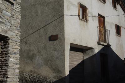 photograph “I.2024 — Faces of home, 259” par David Farreny — www.farreny.net — Andorre, Andorra, Canillo, ville, city, bourgade, town, maison, house, vieille, old, ombre, shadow, fenêtres, windows, balcon, balcony, volets, shutters, bois, wood, garage, portail, gate, métal, metal, rambarde, guardrail, angle, coin, corner, ciment, cement, pierre, stone, fil, wire, câble, cable, ruelle, alley, rideau, curtain, plaque, plate