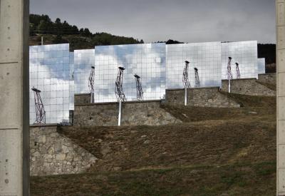 photograph “X.2023” par David Farreny — www.farreny.net — France, Occitanie, Pyrénées-Orientales, Font-Romeu-Odeillo-Via, Odeillo, four solaire, solar furnace, miroirs réfléchissants, reflecting mirrors, perspective, héliostats, heliostats, steerable mirrors, poteaux, poles, posts, béton, concrete, murets, low walls, pierre, stone, structures, métal, metal, colline, hill, arbres, trees, herbe, grass, câbles, cables, fils, wires, nuages, clouds, ciel, sky, reflets, reflections, gris, grey, gray