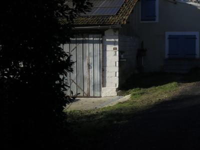 photograph “I.2025 — Faces of home, 260” par David Farreny — www.farreny.net — France, Occitanie, Gascogne, Gascony, Gers, Castelnau-d'Arbieu, maison, house, garage, portail, gate, métal, metal, parpaings, breeze-blocks, angle, coin, corner, fenêtres, windows, volets, shutters, bois, wood, toit, tuiles, tiles, plaques, photovoltaïques, photovoltaic, panels, arbre, tree, herbe, grass, route, road, bitume, blacktop, asphalte, asphalt, plaque, plate, numéro, number, 405