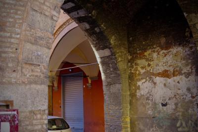 photograph “X.2019” par David Farreny — www.farreny.net — Italie, Italia, Italy, Émilie-Romagne, Emilia-Romagna, Bologne, Bologna, ville, city, rue, street, arcades, arcs, archs, arches, brique, brick, mur, wall, voiture, car, métal, metal, store, décrépit, decrepit, chapeaux, hats, fenêtre, window, verre, vitre, glass