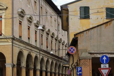 photograph “X.2019” par David Farreny — www.farreny.net — Italie, Italia, Italy, Émilie-Romagne, Emilia-Romagna, Bologne, Bologna, arcades, arcade, pierre, stone, brique, brick, câbles, cables, fils, wires, ville, city, panneaux, signs, routiers, roadsigns, flèche, arrow, haut, up, parking, car park, fenêtres, windows, volets, shutters, carrefour, crossing, coins, corners, angles, tag, graffiti, balcon, balcony, gouttières, drainpipes, métal, metal, lampes, lamps, profusion