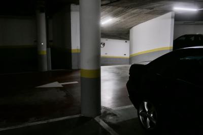 photograph “X.2023” par David Farreny — www.farreny.net — Andorre, Andorra, Canillo, parking, car park, souterrain, underground, béton, concrete, voitures, cars, roue, wheel, métal, metal, colonne, column, pilier, pillar, lumière, light, néon, neon, murs, walls, jaune, yellow, lignes, lines, pénombre, darkness, sombre, dark, flèche, arrow, gauche, left, miroir, mirror, rampe, ramp