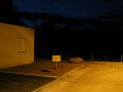 photograph “VIII.2013 — Night” par David Farreny — www.farreny.net — France, nuit, night, maison, house, béton, concrete, boîte à lettres, letterbox, mailbox, métal, metal, fenêtre, window, volet, shutter, rocher, rock, clôture, fence, terre, sol, earth, soil, gravier, gravel, lumière, light, jaune, yellow, obscur, dark, obscurité, darkness, ville, city, Occitanie, Rouergue, Aveyron, Olemps