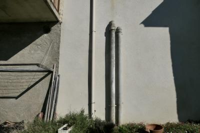 photograph “VIII.2024 — Whatever” par David Farreny — www.farreny.net — France, Occitanie, Gascogne, Gascony, Gers, Biran, mur, wall, ciment, cement, tuyaux, pipes, métal, metal, ombre, shadow, balcon, balcony, étendoir, clothes rack, herbe, grass, pots, fleurs, flowers, bâtons, sticks, dépression, depression