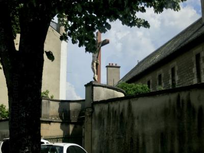 photograph “VI.2014” par David Farreny — www.farreny.net — France, rue, street, arbre, tree, mur, wall, ciment, cement, immeubles, bâtiments, buildings, voitures, cars, Christ, Jésus, Jesus, croix, cross, feuilles, leaves, feuillage, foliage, grille, railings, toit, roof, statue, tronc, trunk, cheminée, chimney, ville, city, Occitanie, Rouergue, Aveyron, Rodez