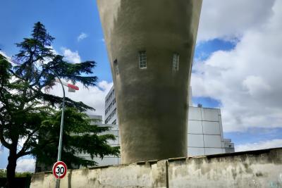 photograph “VII.2024” par David Farreny — www.farreny.net — France, Occitanie, Haute-Garonne, Toulouse, Bonnefoy, Matabiau, bâtiment, immeuble, building, béton, concrete, mur, paroi, wall, ciment, cement, métal, metal, arbre, tronc, trunk, tree, cèdre, cedar, branches, lampadaire, lamp, château d'eau, water tower, grue, crane, panneau, sign, routier, roadsign, vitesse, speed, 30, nombre, number, fenêtres, windows, humidité, moisture, nuages, clouds