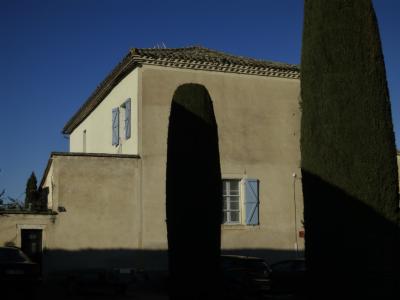 photograph “II.2025 — Faces of home, 253” par David Farreny — www.farreny.net — France, Occitanie, Tarn, Castelnau-de-Montmiral, village, maison, house, génoises, cyprès, cypresses, arbres, trees, voitures, cars, soir, evening, fenêtres, windows, volets, shutters, bois, wood, verre, vitre, glass, mur, wall, jaune, yellow, beige, toit, roof, tuiles, tiles, antenne, antenna, ombre, shadow, câble, cable, fil, wire, domicile, home