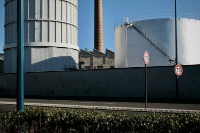 photograph “I.2011” par David Farreny — www.farreny.net — France, Auvergne, Puy-de-Dôme, Clermont-Ferrand, Montferrand, usine, factory, Michelin, béton, concrete, brique, brick, métal, metal, cheminée, chimney, cuves, citernes, réservoirs, tanks, reservoirs, industrie, industry, route, road, panneaux, signs, 70, lampadaires, réverbères, lamps, street lamps, haie, hedge, hiver, winter, froid, cold, toits, toiture, redans, shed, sheds, dents de scie, serrated, jagged, roof, roofing, limitation, vitesse, speed, limit, mur, wall, escalier, stairs, rambarde, guardrail, DF1