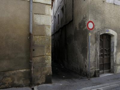 photograph “X.2016” par David Farreny — www.farreny.net — France, Occitanie, Gascogne, Gers, Auch, rue, street, ville, city, ruelle, alley, pierre, stone, étroit, narrow, panneau, sign, routier, roadsign, porte, door, bois, wood, fenêtres, windows, gouttière, drainpipe, coin, corner, angle, trottoir, pavement, bitume, blacktop, asphalte, asphalt, ombre, darkness, humide, damp, volets, shutters, 9, plaque, plate, numéro, number