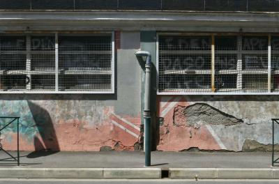 photograph “VII.2024 — Whatever” par David Farreny — www.farreny.net — France, Occitanie, Haute-Garonne, Toulouse, Matabiau, Bonnefoy, ville, city, rue, street, mur, wall, gouttière, drainpipe, tuyau, pipe, métal, metal, trottoir, pavement, béton, concrete, barrières, guardrails, grillage, fencing, tags, graffitis, ombres, shadows, peinture, paint, ciment, cement