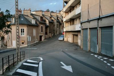 photograph “XII.2011 — Approaches to Christmas, 8” par David Farreny — www.farreny.net — France, rues, streets, carrefour, crossroads, crossing, béton, concrete, ciment, cement, ville, city, maisons, houses, immeuble, building, grillage, fencing, balcons, balconies, panneaux, routiers, roadsigns, gouttière, drainpipe, garages, portails, gates, poteau, électrique, electricity, pole, flèche, arrow, hachures, hatching, passage piétons, zebra, rambarde, guardrail, voiture, car, sens interdit, one-way, fenêtres, windows, boîte à lettres, post box, mailbox, fils, câbles, wires, cables, métal, metal, Noël, Christmas, Occitanie, Aveyron, Rouergue