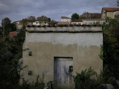 photograph “X.2016” par David Farreny — www.farreny.net — France, maisons, houses, village, remise, shed, mur, wall, arbres, trees, toit, roof, tuiles, tiles, fils, wires, câbles, cables, électriques, electrical, porte, door, bois, wood, grillage, fencing, profusion, Occitanie, Gascogne, Gers, Jegun