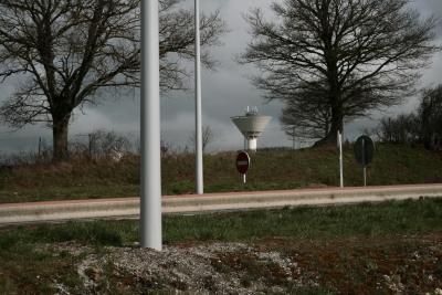 photograph “III.2010” par David Farreny — www.farreny.net — France, route, road, rocade, highway, lampadaires, réverbères, lamps, street lamps, poteaux, poles, arbres, trees, panneaux, roadsigns, traffic signs, terre-plein central, median strip, central reservation, château d'eau, water tower, Occitanie, Aveyron, Rouergue, Olemps