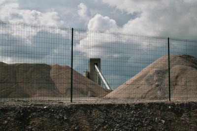 photograph “IX.2011” par David Farreny — www.farreny.net — France, industrie, industry, usine, factory, béton, concrete, gravier, gravel, sable, sand, tas, heaps, grillage, clôture, fence, fencing, rampe, ramp, slope, tapis roulant, convoyeur à bande, conveyor belt, nuages, clouds, Occitanie, Aveyron, Rouergue, Sébazac-Concourès