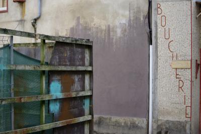 photograph “III.2021” par David Farreny — www.farreny.net — France, Occitanie, Gascogne, Gers, Éauze, ville, city, rue, street, coin, corner, angle, chantier, works, palissade, palisade, bois, wood, métal, metal, mur, wall, maison, house, magasin, store, shop, boucherie, butcher's, butcher, enseigne, sign, lettres, letters, caractères, characters, carrelage, tiling, mosaïque, mosaic, câbles, cables, fils, wires, gouttière, drainpipe, peinture, paint, fenêtre, window, pierre, stone, panneau, flèche, arrow, chapelle et jardin du pèlerin, pilgrim's chapel and garden, ciment, cement