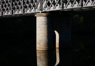 photograph “XI.2005” par David Farreny — www.farreny.net — France, Occitanie, Aveyron, Rouergue, Capdenac-Gare, Lot, rivière, river, eau, water, pont, bridge, ferroviaire, rail, railway, voie ferrée, métal, metal, pierre, stone, rivets, arche, arch, arc, brisé, pointed, reflet, reflection, pénombre, darkness, sombre, dark