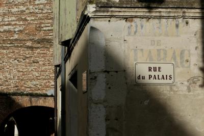 photograph “I.2020” par David Farreny — www.farreny.net — France, Occitanie, Gascogne, Tarn-et-Garonne, Auvillar, village, bourgade, town, angle, coin, corner, rue, street, murs, walls, brique, brick, volets, shutters, bois, wood, arche, arch, plaque, plate, rue du Palais, publicité, pub, advertising, ad, débit de tabac, tobacco shop, vieux, old, pierre, stone, gouttières, drainpipes