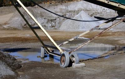 photograph “X.2006 — Old Sunday” par David Farreny — www.farreny.net — France, Occitanie, Rouergue, Aveyron, Bertholène, Laissac, dimanche, Sunday, carrière, quarry, gravier, gravel, tas, pile, heap, tapis roulant, conveyor belt, convoyeur à bande, métal, metal, industrie, industry, structure, transport, roues, wheels, pneus, tires, flaque, puddle, eau, water, sable, sand