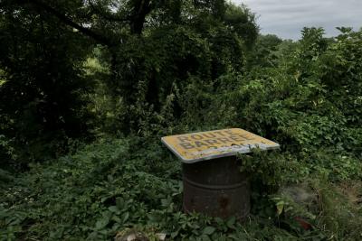 photograph “VIII.2024 — Existential warning” par David Farreny — www.farreny.net — France, Occitanie, Gascogne, Gascony, Gers, Biran, arbres, trees, végétation, vegetation, désordre, disorder, bidon, métal, metal, can, rouille, rust, rusty, panneau, sign, routier, roadsign, route barrée, road closed, inscription, avertissement, warning, dépression, depression