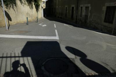 photograph “X.2015” par David Farreny — www.farreny.net — France, Occitanie, Gascogne, Gascony, Gers, Auch, automne, autumn, rue, street, carrefour, croisement, crossing, bitume, blacktop, asphalte, asphalt, autoportrait, selfportrait, ombre, shadow, grille, railings, flèches, arrows, panneaux, signs, routiers, roadsigns, bâtiment, immeuble, fenêtres, windows, portes, doors, mur, wall