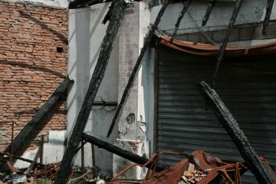 photograph “IV.2010” par David Farreny — www.farreny.net — France, Occitanie, Haute-Garonne, Villemur-sur-Tarn, garage, incendie, fire, feu, portail, gate, métal, metal, poutres, beams, carbonisées, charred, voiture, car, carcasse, body, rouille, rust, rusty, brique, brick, débris, debris, dépression, depression