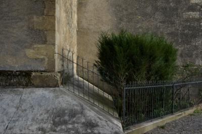 photograph “XII.2015” par David Farreny — www.farreny.net — France, église, church, coin, corner, mur, wall, pierre, stone, haie, hedge, clôture, fence, fencing, métal, metal, gravier, gravel, angle, Occitanie, Gascogne, Gascony, Gers, Jegun