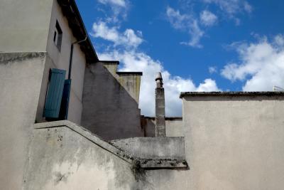 photograph “IX.2024 — Faces of home, 262” par David Farreny — www.farreny.net — France, Occitanie, Tarn-et-Garonne, Nègrepelisse, village, mur, wall, ciment, cement, gris, grey, gray, maison, house, gouttière, drainpipe, fenêtres, windows, volets, shutters, bois, wood, cheminée, chimney, ciel, sky, nuages, clouds, domicile, home