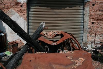 photograph “IV.2010” par David Farreny — www.farreny.net — France, Occitanie, Haute-Garonne, Villemur-sur-Tarn, garage, incendie, fire, feu, portail, gate, métal, metal, gondolé, warped, déformé, distorted, poutres, beams, carbonisées, charred, voiture, car, carcasse, body, rouille, rust, rusty, brique, brick, débris, debris