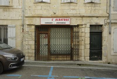 photograph “II.2025 — Souvenirs : souvenir” par David Farreny — www.farreny.net — France, Occitanie, Gascogne, Gascony, Gers, Lomagne, Lectoure, rue, street, bitume, blacktop, asphalte, asphalt, voiture, car, métal, metal, gouttières, drainpipes, fenêtres, windows, volets, shutters, bois, wood, magasin, shop, store, fermé, closed down, grille, railings, pierre, stone, vitrine, baie, bay, verre, vitre, glass, porte, door, plaque, plate, numéro, number, 99, câbles, cables, fils, wires, trottoir, pavement, enseigne, sign, L'Albatros, cadeaux, souvenirs, gifts, tabac, tobacco, effacé, erased, dépression, depression