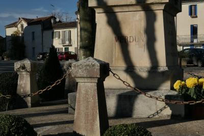 photograph “XI.2020” par David Farreny — www.farreny.net — France, Occitanie, Gascogne, Gers, Jegun, village, maisons, houses, monument, morts, war, memorial, Verdun, pierre, stone, chaînes, chains, métal, metal, fleurs, flowers, inscription, arbre, tree, ombre, shadow, voitures, cars, balcon, balcony, fenêtres, windows, platane, plane tree, socle, pedestal, toits, roofs, volets, shutters, tronc, trunk, branches