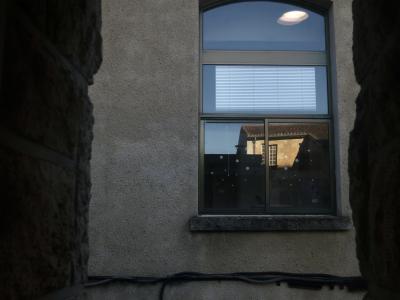 photograph “XII.2016 — Remembrance of waged boredom” par David Farreny — www.farreny.net — France, Occitanie, Gascogne, Gascony, Gers, Auch, bâtiment, building, mur, wall, crépi, roughcast, fenêtre, window, bureau, office, câbles, cables, vitre, verre, glass, reflet, reflection, toit, roof, tuiles, tiles, store, lampe, lamp, salariat, wage