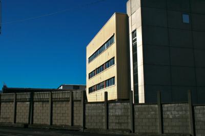 photograph “I.2011” par David Farreny — www.farreny.net — France, Auvergne, Puy-de-Dôme, Clermont-Ferrand, Montferrand, usine, factory, Michelin, mur, wall, béton, concrete, gris, grey, gray, bâtiment, immeuble, building, tôle ondulée, corrugated iron, métal, metal, fenêtres, windows, fil, barbelé, barbed, wire, cubes, industrie, industry, câble, cable, électrique, electrical, Cataroux, laid, laideur, ugly, ugliness